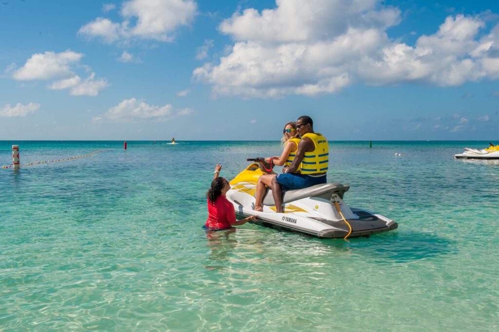 Man and woman on jetski with instructor in water