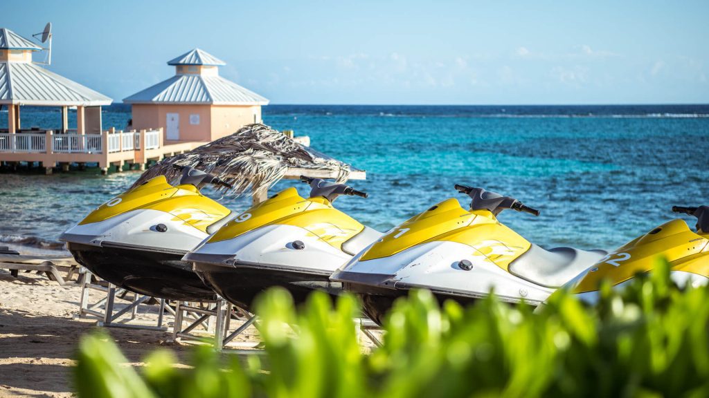 A row of jet skis parked on the sandy beach, ready for an exciting ride on the water.